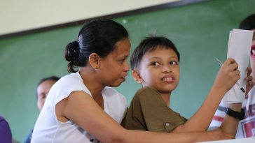 The photo shows a mother assisting her son. Photo by Save the Children Philippines